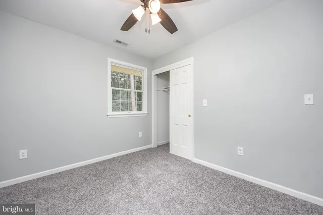 an empty room with a chandelier fan and windows