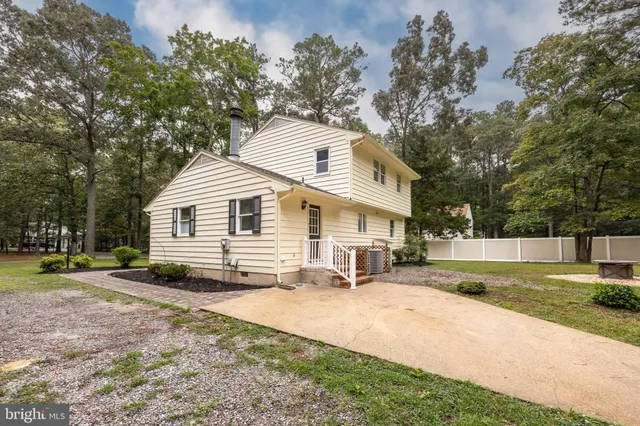 a view of a white house with a yard and sitting area