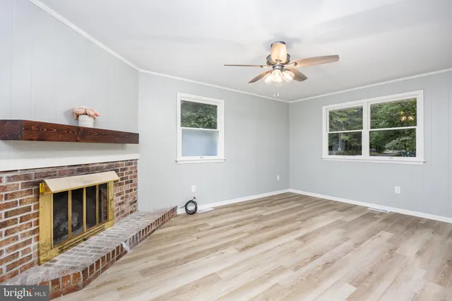 a view of empty room with wooden floor fireplace and fan
