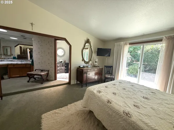 a bedroom with a bed a mirror on dresser and a large window