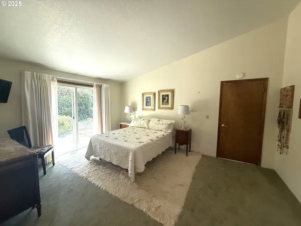 a spacious bedroom with a bed and a flat tv screen next to a window