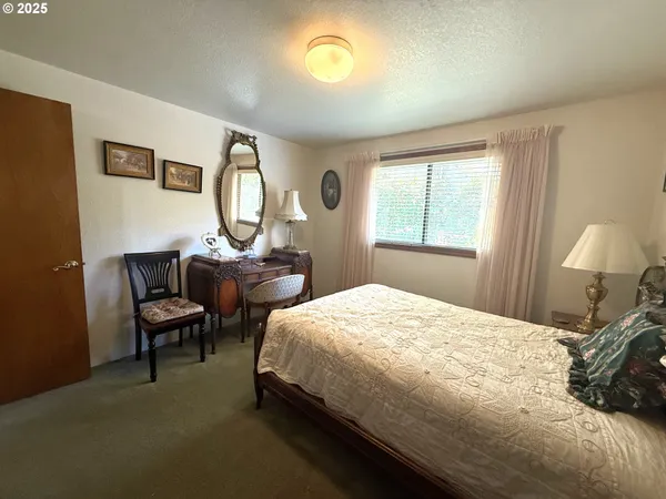 a bedroom with a bed chair and a large window