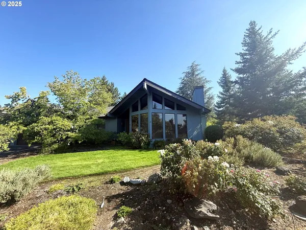 a view of a house with a big yard and large trees