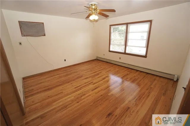an empty room with wooden floor and fan