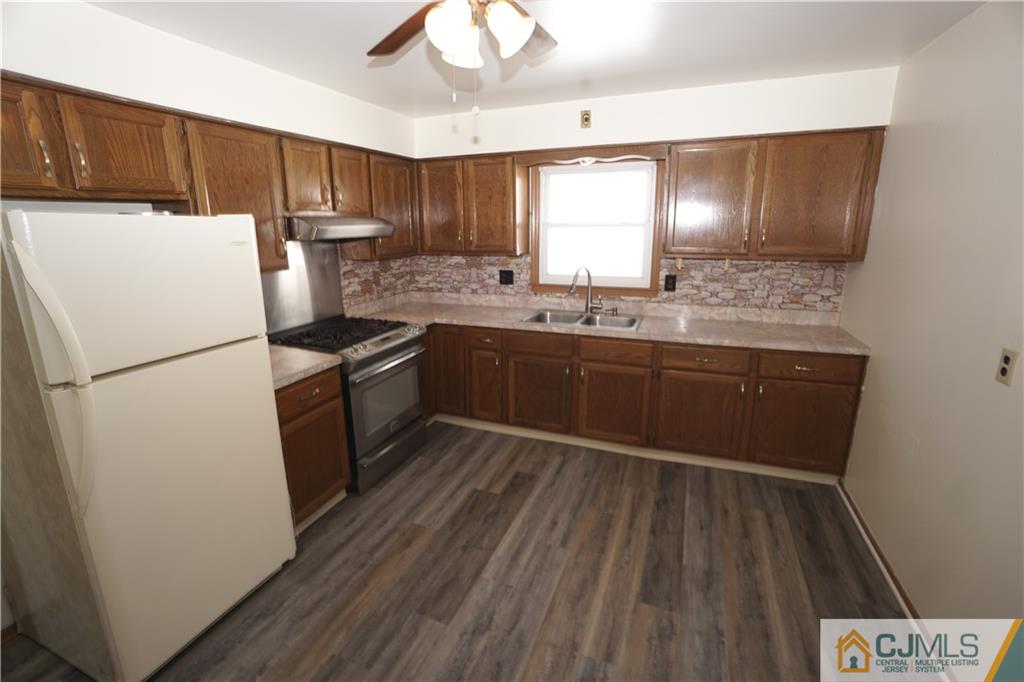 400 Washington Avenue Linden, NJ 07036 - Photo 6 of 18 a kitchen with wooden cabinets and white appliances