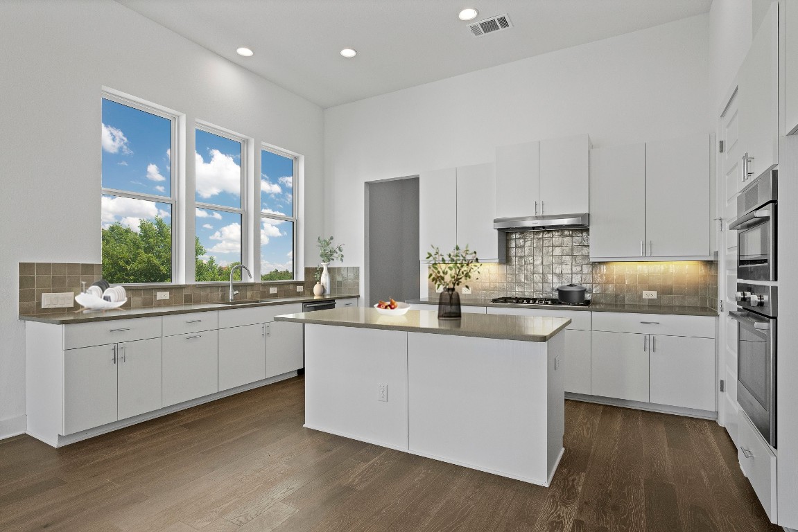 a kitchen with stainless steel appliances a sink a stove a refrigerator and white cabinets