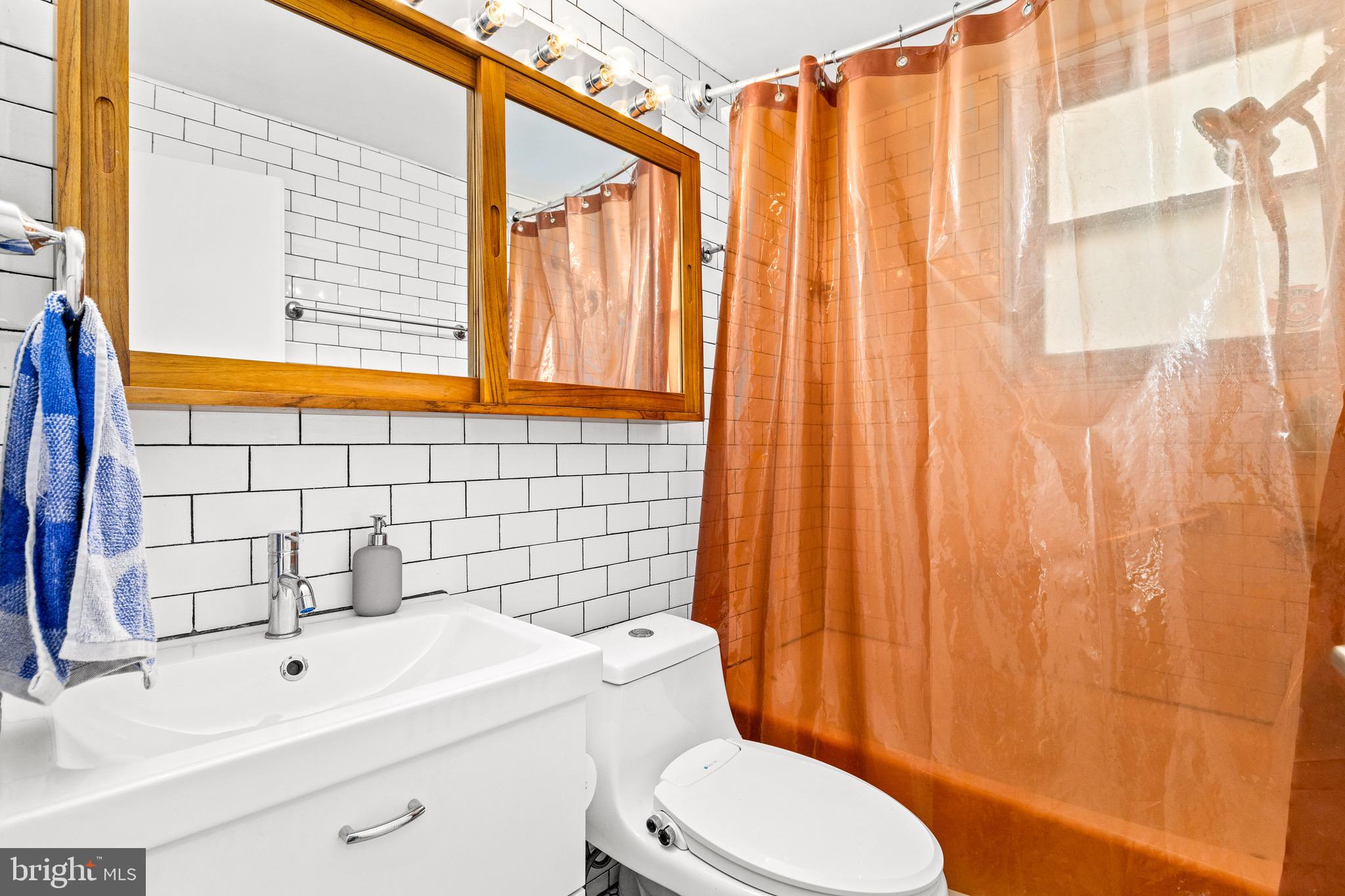 3025 Ontario Road Northwest, Unit 207 Washington, DC 20009 - Photo 11 of 15 a bathroom with a sink a toilet and shower curtain
