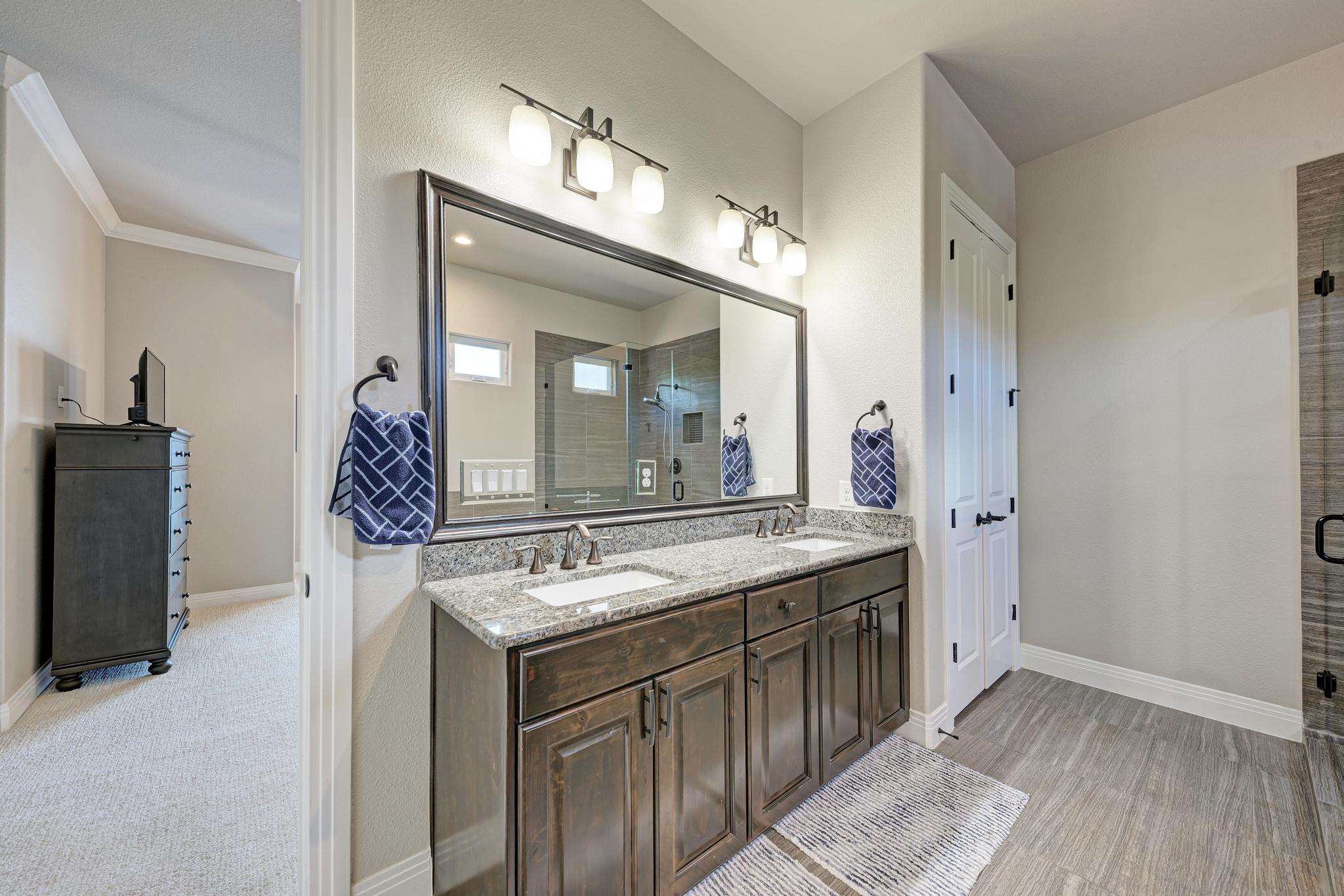 2601 North Quinlan Park Road, Unit 506 Austin, TX 78732 - Photo 25 of 39 Granite counters and dual sinks define this primary bathroom, featuring a large mirror and modern lighting.