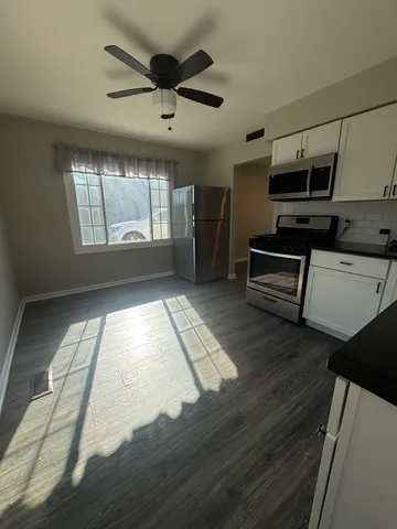 a living room with stainless steel appliances kitchen island granite countertop a stove a refrigerator and a cabinets