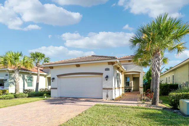 a view of a house with a yard and palm trees