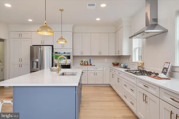 a kitchen with stainless steel appliances granite countertop a sink a stove a refrigerator cabinets and chairs