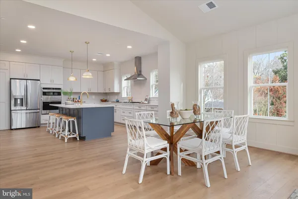 a dining room with stainless steel appliances kitchen island granite countertop a table chairs and a refrigerator