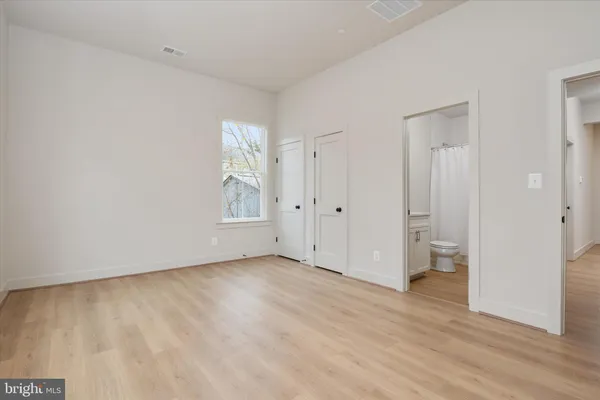 a view of an empty room with wooden floor and closet