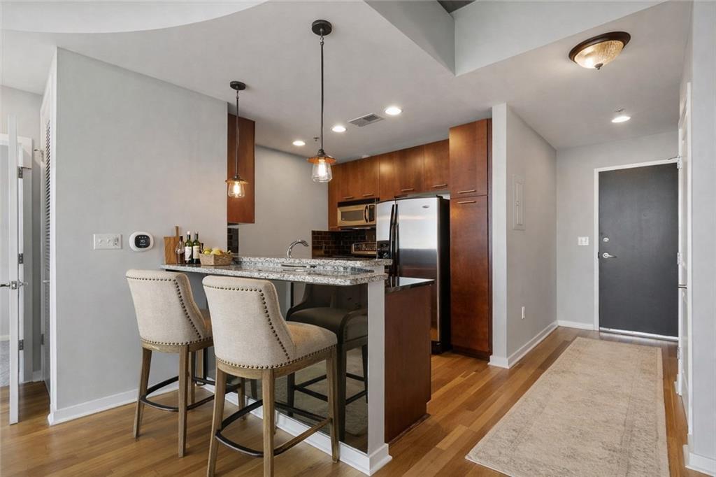3324 Peachtree Road Northeast, Unit 2804 Atlanta, GA 30326 - Photo 6 of 34 a kitchen with stainless steel appliances kitchen island granite countertop a refrigerator a stove a microwave oven a sink with island and chairs