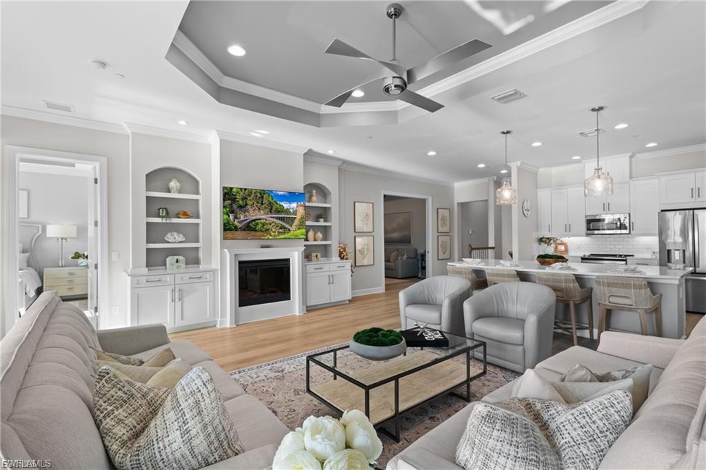 9642 Montelanico Loop, Unit 201 Naples, FL 34119 - Photo 22 of 27 a living room with furniture a fireplace and a chandelier
