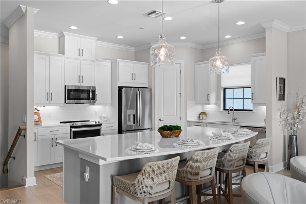 9642 Montelanico Loop, Unit 201 Naples, FL 34119 - Photo 25 of 27 a kitchen with stainless steel appliances granite countertop a kitchen island hardwood floor and chairs