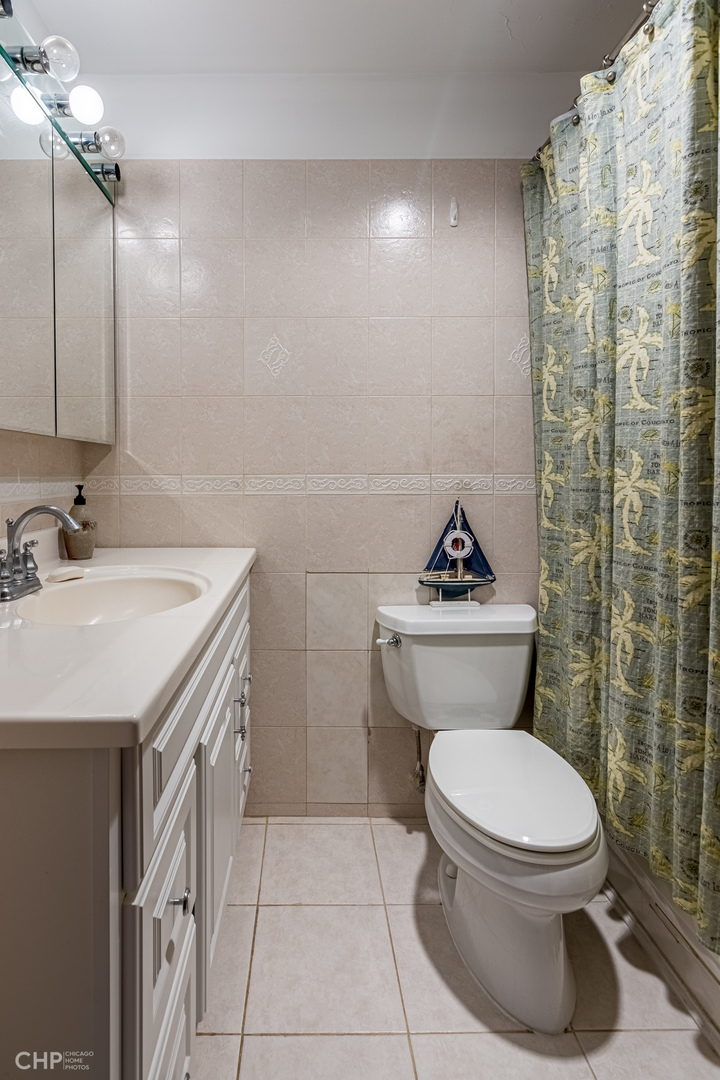 5455 North Sheridan Road, Unit 710 Chicago, IL 60640 - Photo 7 of 11 a bathroom with a toilet sink and mirror