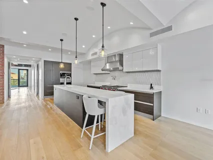 a kitchen with stainless steel appliances kitchen island granite countertop a sink a stove a refrigerator and island with wooden floor