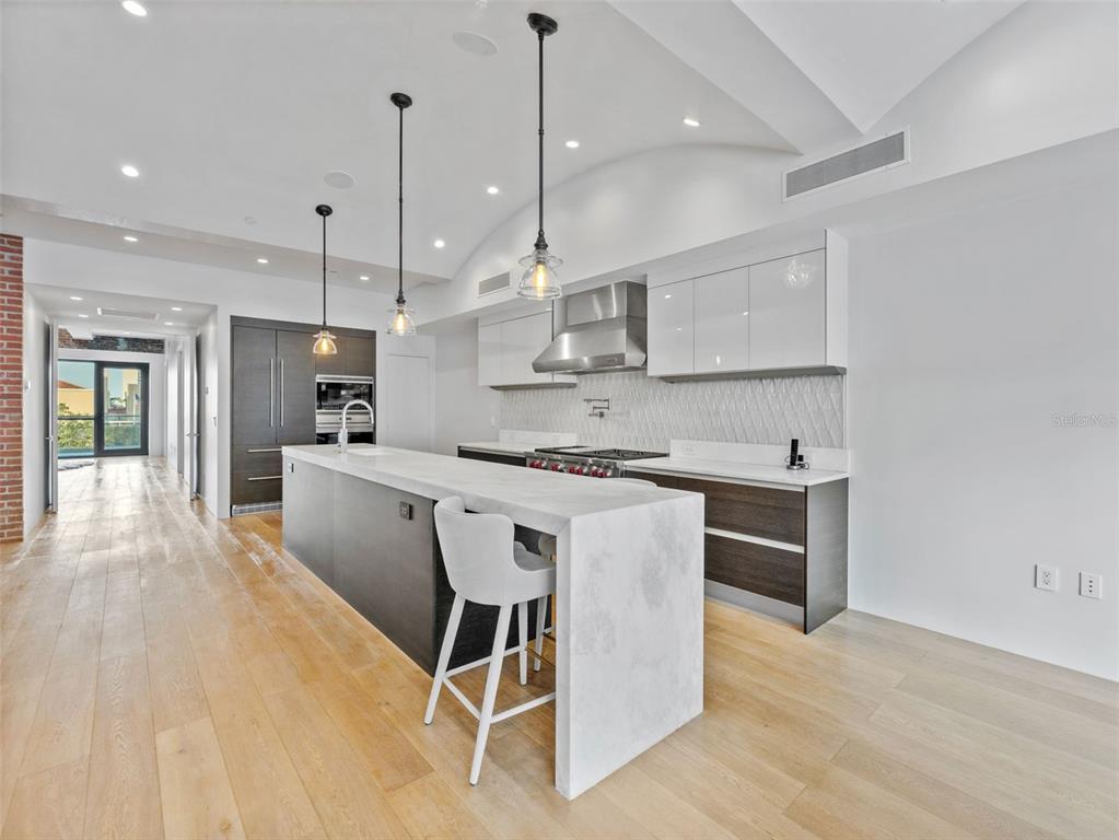 465 Central Avenue, Unit 301 St. Petersburg, FL 33701 - Photo 3 of 47 a kitchen with stainless steel appliances kitchen island granite countertop a sink a stove a refrigerator and island with wooden floor