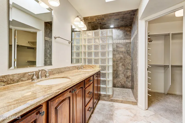 a bathroom with a granite countertop sink a mirror and shower