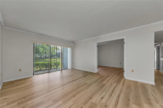 a view of an empty room with wooden floor and window