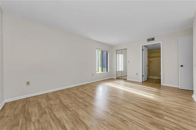 a view of empty room with wooden floor and fan