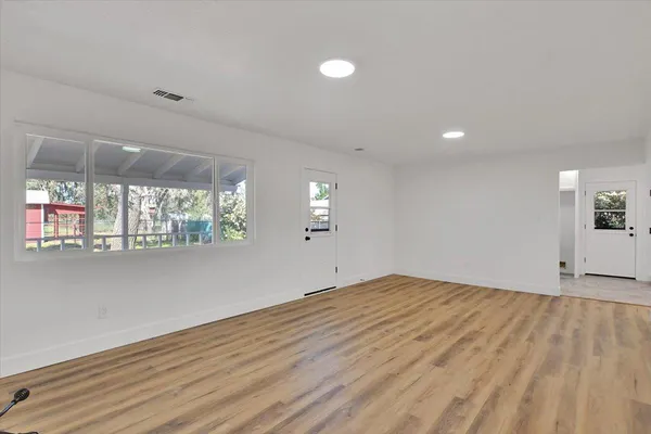 an empty room with wooden floor and windows