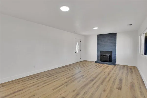 a view of empty room with wooden floor and fireplace