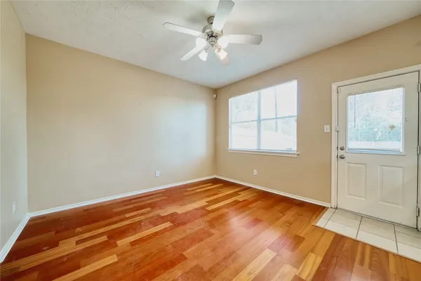 a view of an empty room with window and wooden floor