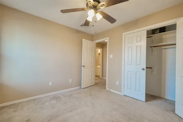 an empty room with closet and a chandelier fan
