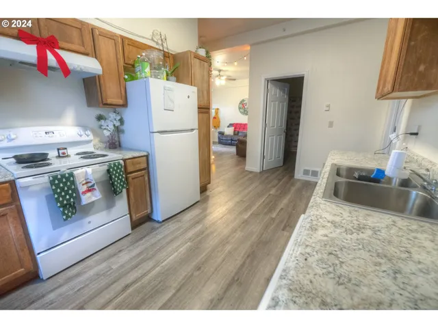 a kitchen with a refrigerator a stove and wooden floor