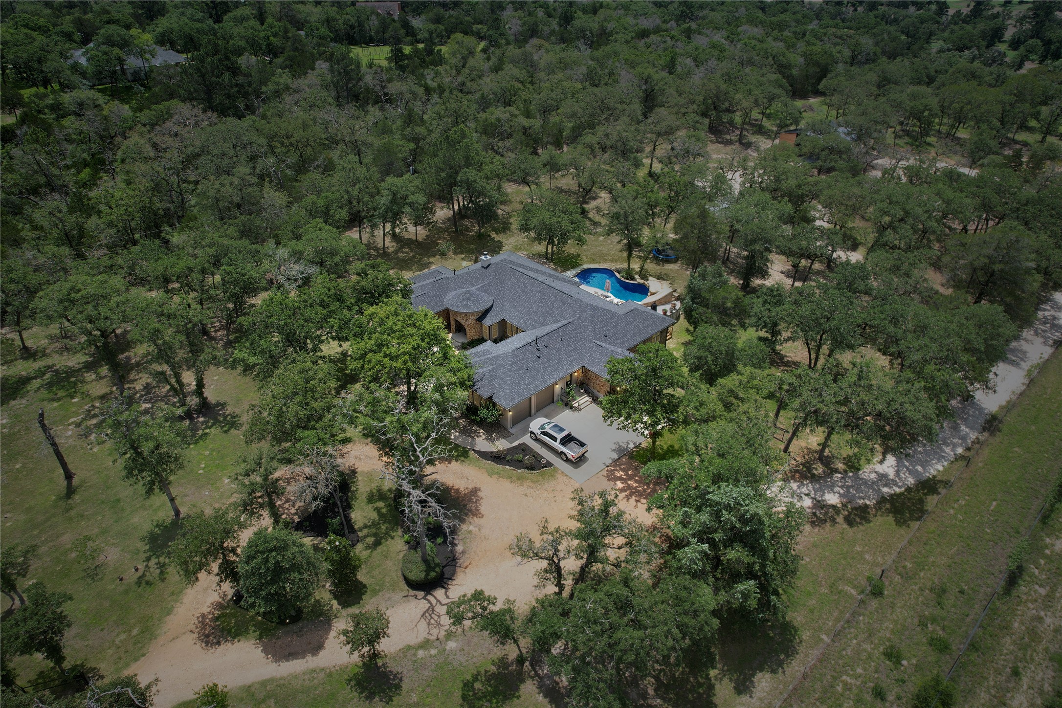 387 Corral Road Smithville, TX 78957 - Photo 6 of 40 Expansive property featuring a single-story residence with a dark shingle roof, a circular driveway, and a private swimming pool