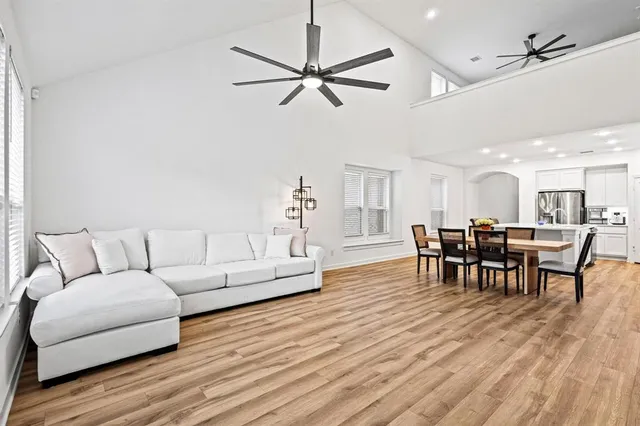 a living room with furniture kitchen view and a wooden floor