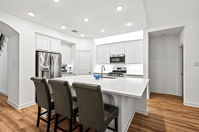 a kitchen with stainless steel appliances a table chairs refrigerator and microwave