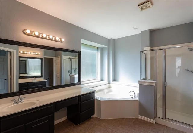 a bathroom with a tub a sink and a large mirror
