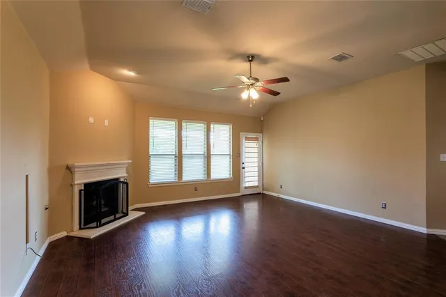 a view of an empty room with wooden floor and a fireplace