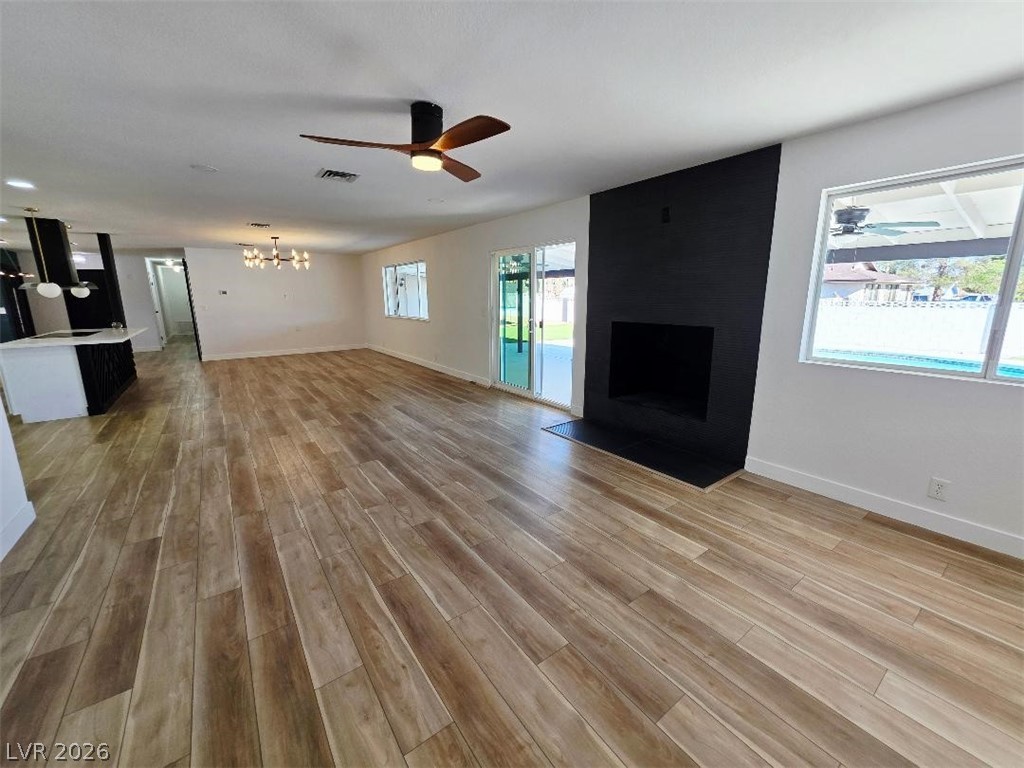 3420 West Warm Springs Road Las Vegas, NV 89118 - Photo 15 of 50 living room featuring ceiling fan, a fireplace, light wood finished floors, and a chandelier