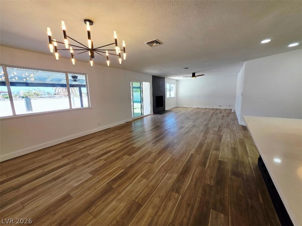 3420 West Warm Springs Road Las Vegas, NV 89118 - Photo 22 of 50 living room with a ceiling fan, a textured ceiling, dark wood-style flooring, hanging lights, and a fireplace