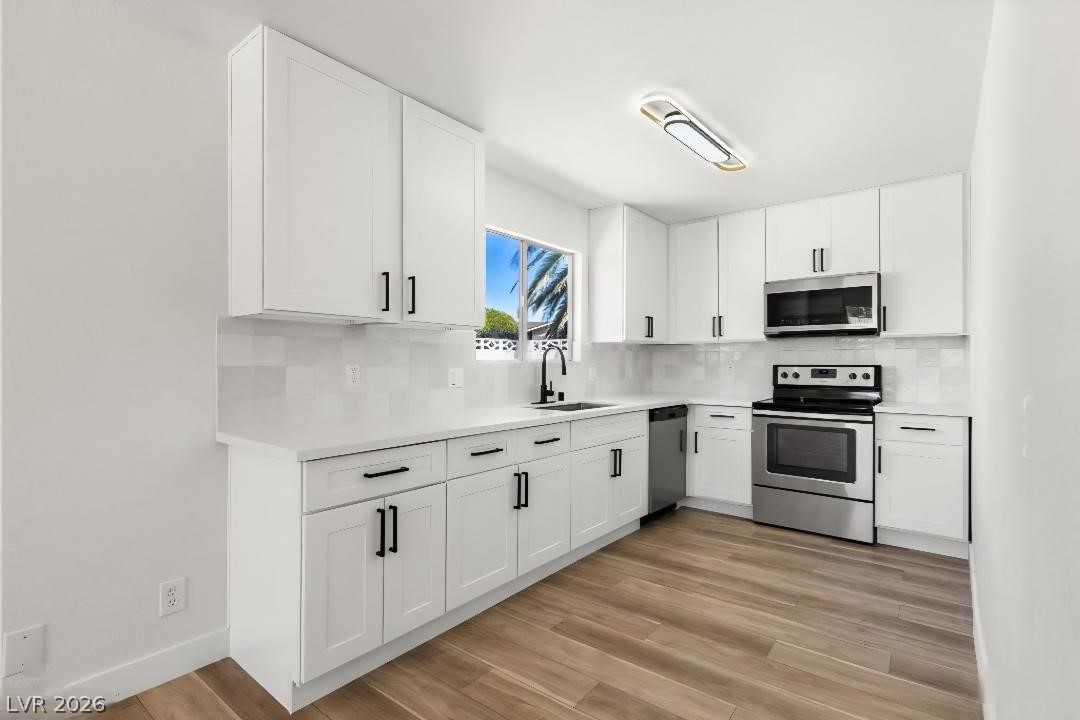 3420 West Warm Springs Road Las Vegas, NV 89118 - Photo 34 of 50 Casita Kitchen featuring white cabinetry, stainless steel appliances, backsplash, and light wood finished floors