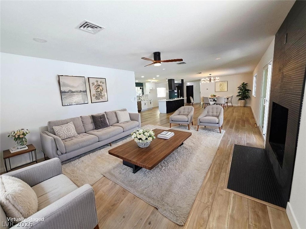 3420 West Warm Springs Road Las Vegas, NV 89118 - Photo 5 of 50 Living area featuring light wood-style floors and a ceiling fan , wood burning fireplace 25x15 Virtually stage