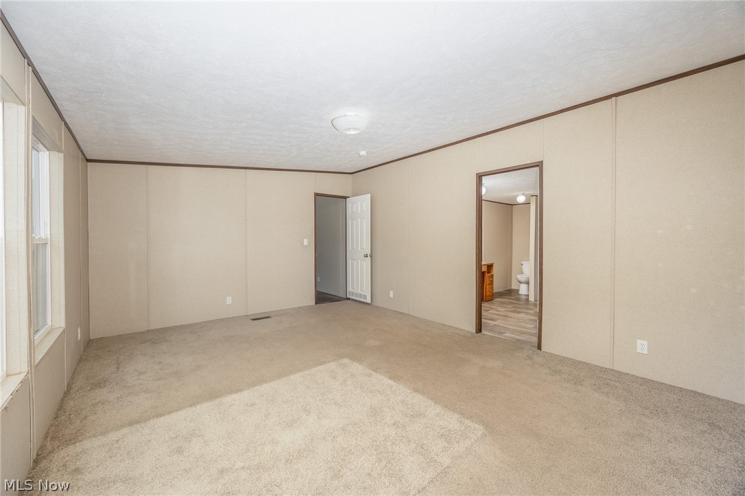 7455 Stanleyville Road Whipple, OH 45788 - Photo 15 of 37 Spacious room featuring neutral carpet flooring, light-toned wall panels with dark trim, and a ceiling-mounted light fixture