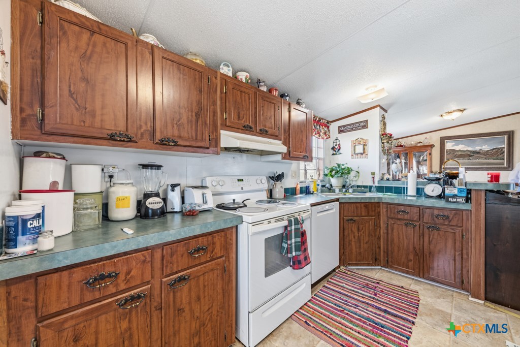 2632 Slickfield Road Yorktown, TX 78164 - Photo 10 of 33 a kitchen with granite countertop stainless steel appliances stove and cabinets