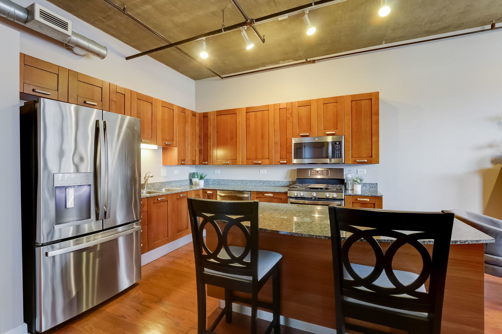 111 South Morgan Street, Unit 505 Chicago, IL 60607 - Photo 6 of 23 a kitchen with stainless steel appliances granite countertop a stove a refrigerator a sink a stove with island chairs and wooden cabinets