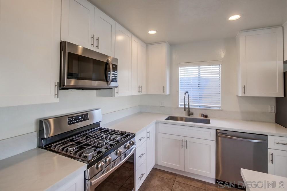 1122 11th Street Imperial Beach, CA 91932 - Photo 5 of 23 a kitchen with white cabinets a sink dishwasher and a stove with wooden floor