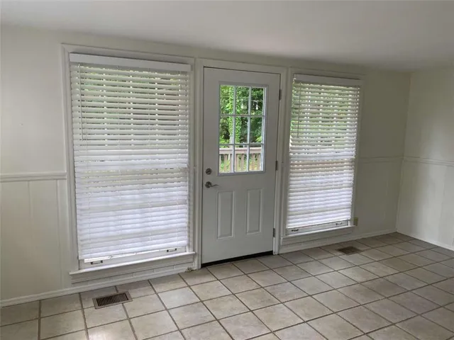 a view of an empty room with window and chandelier fan