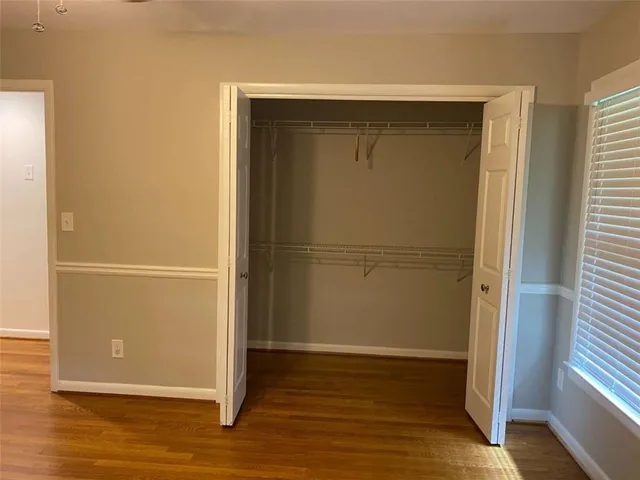 an empty room with wooden floor closet and windows