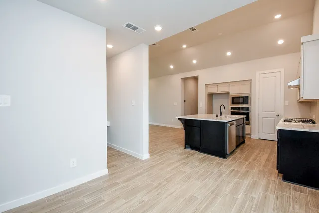 a large kitchen with kitchen island a sink wooden floor and stainless steel appliances