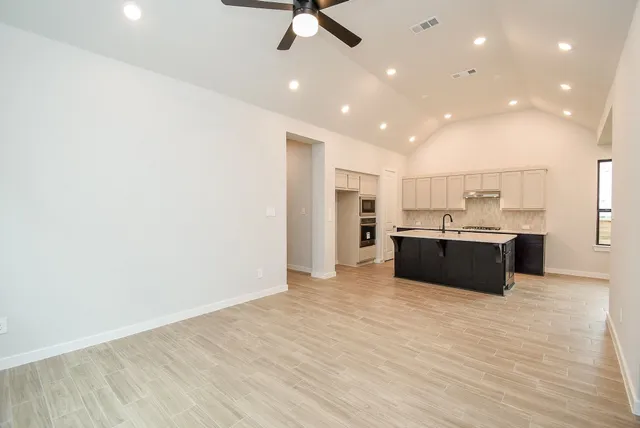 a view of an empty room with a window and a kitchen