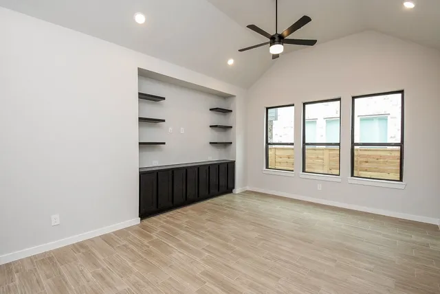 a view of an empty room with a window and wooden floor