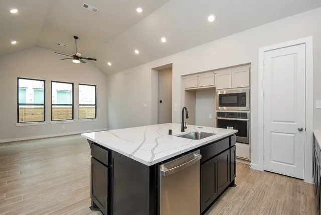 a kitchen that has a sink a oven and wooden floor